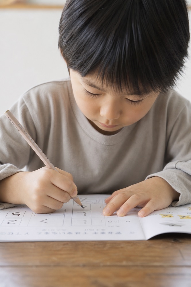 机に向かってワークに書き込む子ども